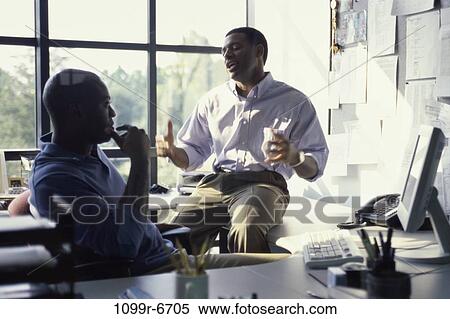 Two businessmen talking in an office View Large Photo Image Stock Photography - Two businessmen talking in an office. Fotosearch