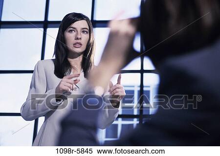 Two businesswomen discussing in an office View Large Photo Image Stock Photography - Two businesswomen discussing in an office. Fotosearch