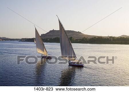 Two feluccas sail down the Nile River at sunset at Aswan, Egypt View Large Photo Image Stock Image - Two feluccas sail down the Nile River at sunset at Aswan, Egypt. Fotosearch