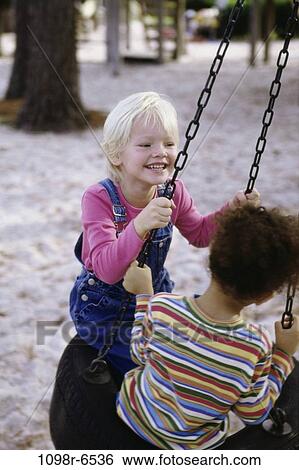 Two girls playing on a tire swing View Large Photo Image Stock Photograph - Two girls playing on a tire swing. Fotosearch