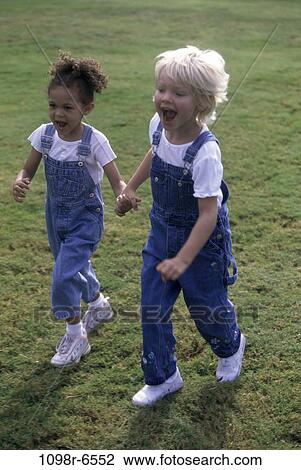 Stock Image - Two girls running on a lawn. Fotosearch