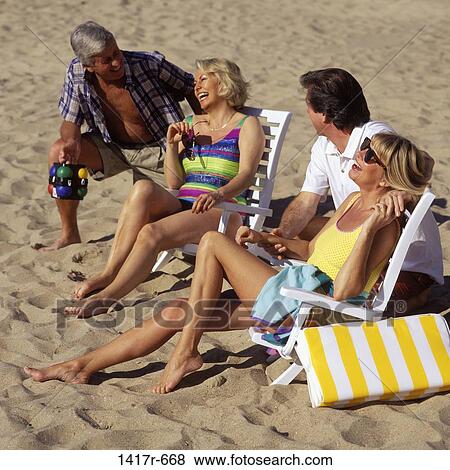 Two mid adult couples sitting together on the beach View Large Photo Image Stock Photo - Two mid adult couples sitting together on the beach. Fotosearch