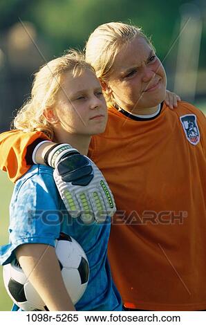 Stock Photography - Two teenage girls standing together with their arms around each other. Fotosearch