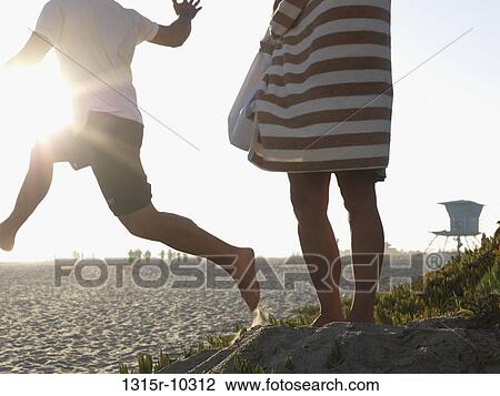 USA, California, San Diego, Man jumping from sand dune while woman watches View Large Photo Image Stock Image - USA, California, San Diego, Man jumping from sand dune while woman watches. Fotosearch