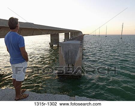 USA, Florida Keys, Islamorada, man looking across water from broken bridge View Large Photo Image Stock Image - USA, Florida Keys, Islamorada, man looking across water from broken bridge. Fotosearch