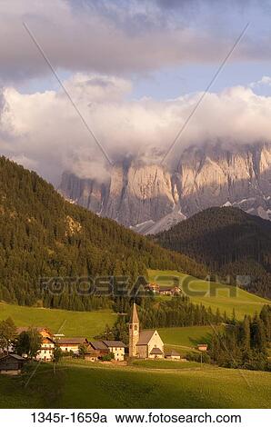 Stock Image - Village with mountain range on a landscape, Santa Maddalena, Funes Valley, Dolomites, Trentino-Alto-Adige, Italy. Fotosearch