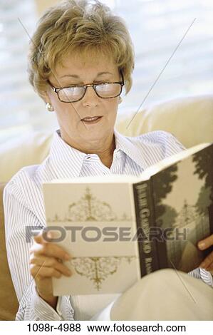 Stock Photo - Woman sitting on a couch reading a book. Fotosearch