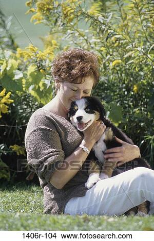 Woman sitting on a lawn hugging a puppy View Large Photo Image Picture - Woman sitting on a lawn hugging a puppy. Fotosearch