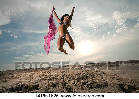 Stock Photograph - Young Brunette Woman at the beach enjoying herself. Fotosearch