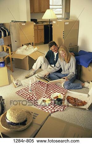 Stock Photography - Young couple eating food on the floor. Fotosearch