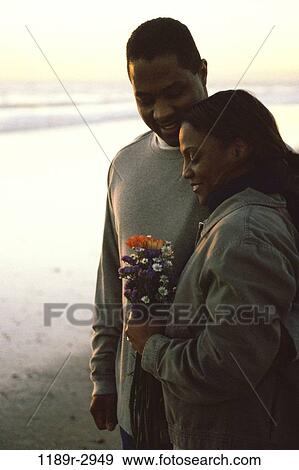 Young couple holding each other at the beach View Large Photo Image Stock Photo - Young couple holding each other at the beach. Fotosearch