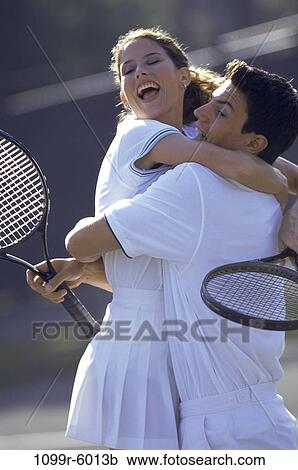 Young couple hugging each other at a tennis court View Large Photo Image Stock Image - Young couple hugging each other at a tennis court. Fotosearch