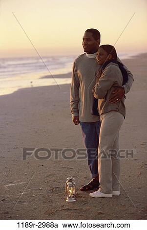 Young couple standing on the beach together View Large Photo Image Stock Image - Young couple standing on the beach together. Fotosearch