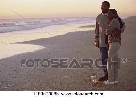 Stock Image - Young couple standing on the beach together. Fotosearch