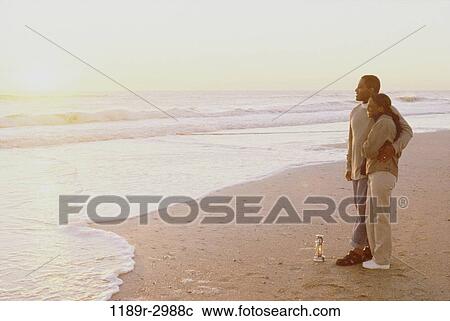 Young couple standing on the beach together View Large Photo Image Stock Image - Young couple standing on the beach together. Fotosearch