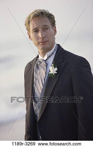 Stock Photo - Young groom standing on the beach. Fotosearch