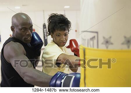 Stock Image - Young male coach coaching a female boxer. Fotosearch