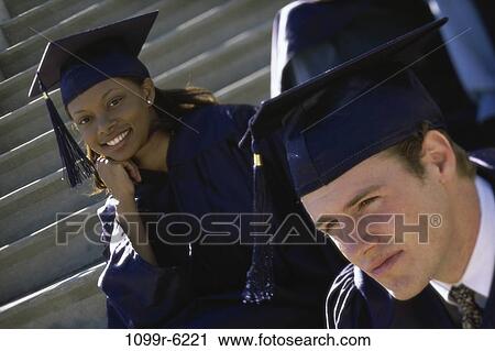 Stock Image - Young male graduate and a young female graduate smiling. Fotosearch
