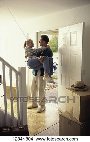 Young man carrying a young woman at the doorway of new house View Large Photo Image Picture - Young man carrying a young woman at the doorway of new house. Fotosearch