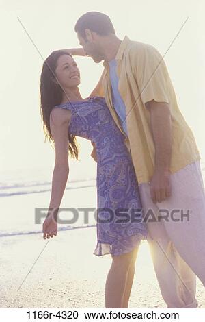 Young man holding a young woman at the beach View Large Photo Image Stock Image - Young man holding a young woman at the beach. Fotosearch
