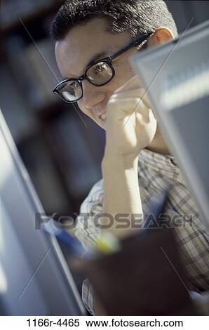 Young man looking at a computer monitor View Large Photo Image Stock Photography - Young man looking at a computer monitor. Fotosearch