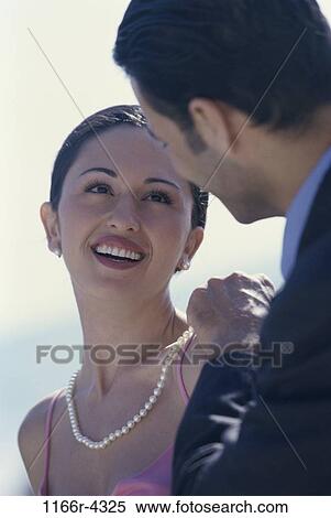 Stock Photography - Young man putting a pearl necklace on a young woman. Fotosearch