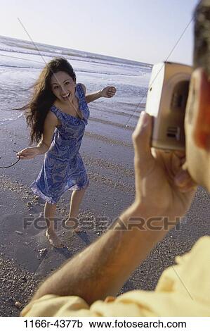 Young man taking a photograph of a young woman at the beach View Large Photo Image Stock Image - Young man taking a photograph of a young woman at the beach. Fotosearch