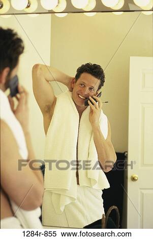 Young man talking on a mobile phone looking into a mirror View Large Photo Image Stock Photography - Young man talking on a mobile phone looking into a mirror. Fotosearch