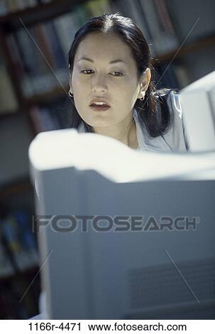 Young woman looking at a computer monitor View Large Photo Image Stock Image - Young woman looking at a computer monitor. Fotosearch