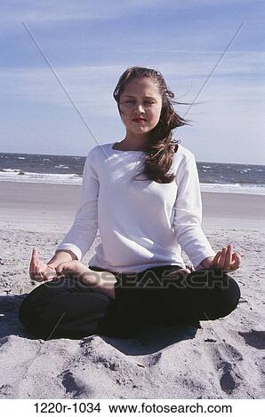 Picture - Young woman meditating on the beach. Fotosearch