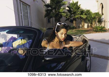 Young woman sitting in a convertible car View Large Photo Image Stock Image - Young woman sitting in a convertible car. Fotosearch