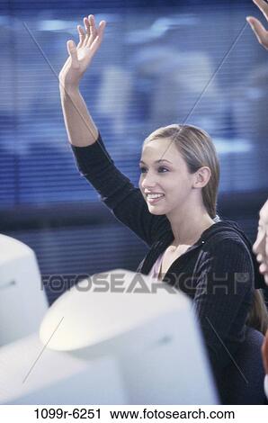 Young woman sitting in front of a computer monitor with her arm raised View Large Photo Image Stock Image - Young woman sitting in front of a computer monitor with her arm raised. Fotosearch