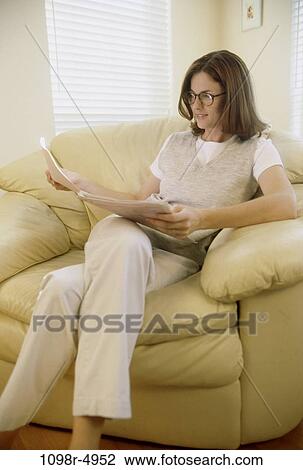Young woman sitting on a couch View Large Photo Image Stock Image - Young woman sitting on a couch. Fotosearch