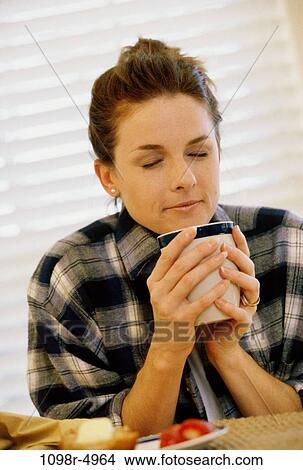 Young woman smelling a cup of coffee View Large Photo Image Picture - Young woman smelling a cup of coffee. Fotosearch