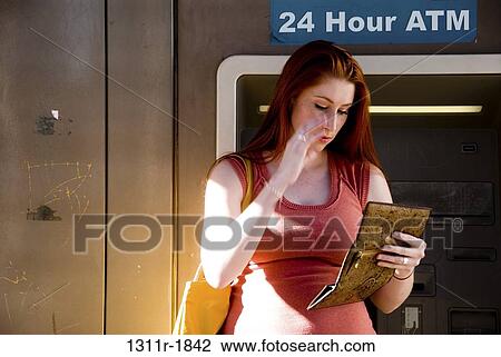 Young woman standing in front of an ATM and looking at her purse View Large Photo Image Stock Image - Young woman standing in front of an ATM and looking at her purse. Fotosearch