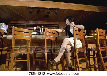 Stock Image - A contemplative young Asian woman sitting at a bar. Fotosearch