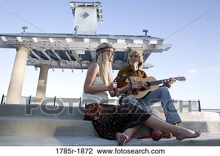 A young Hippie couple in a park playing guitar and tambourine View Large Photo Image Stock Image - A young Hippie couple in a park playing guitar and tambourine. Fotosearch