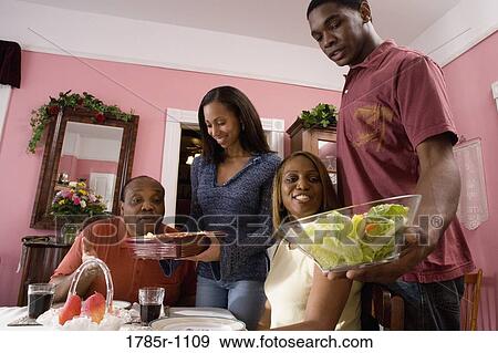 Adult children serving food at family dinner View Large Photo Image Stock Photo - Adult children serving food at family dinner. Fotosearch