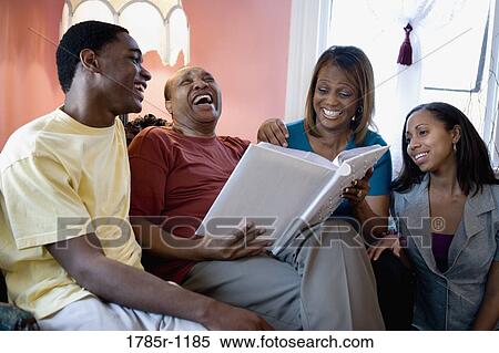 Stock Photography - African American family looking at photo album. Fotosearch