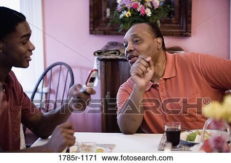 African American father and son at dining table, looking at cellphone View Large Photo Image Stock Image - African American father and son at dining table, looking at cellphone. Fotosearch