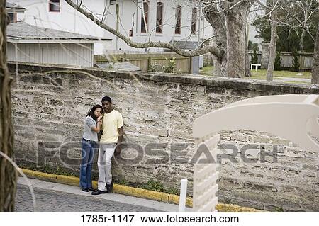 Stock Photo - African American teenagers leaning against wall outside. Fotosearch