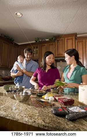 Stock Image - Asian-Caucasian family preparing dinner together. Fotosearch