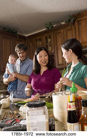Stock Image - Asian-Caucasian family preparing dinner together. Fotosearch