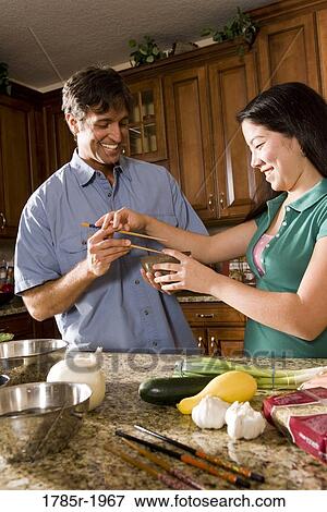 Stock Photo - Asian girl showing man how to use chopsticks. Fotosearch