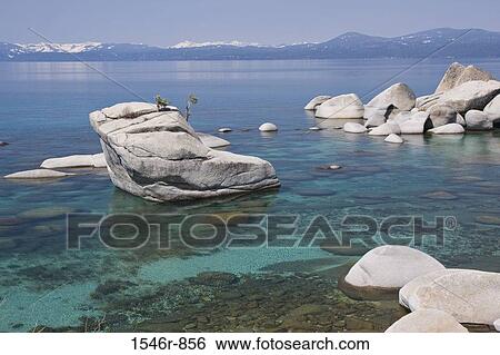Stock Photograph - Bonsai rocks in a lake with mountains in the background, East Shore, Lake Tahoe, Nevada, USA. Fotosearch