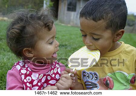 Boy and a girl eating a lollipop View Large Photo Image Stock Image - Boy and a girl eating a lollipop. Fotosearch