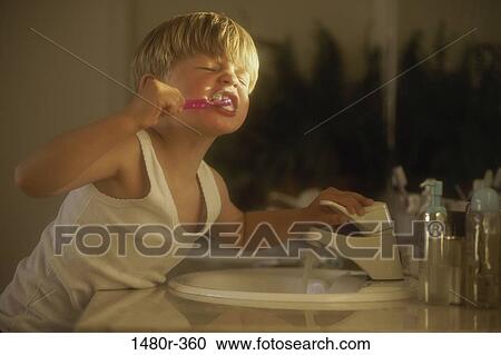 Stock Image - Boy brushing his teeth over a sink. Fotosearch