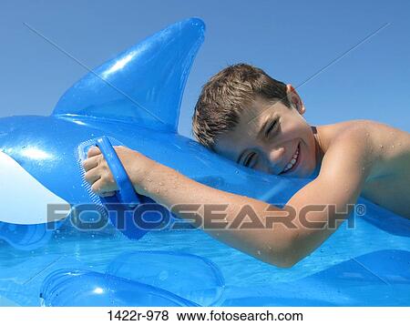 Boy on an inflatable fish in a swimming pool View Large Photo Image Stock Photo - Boy on an inflatable fish in a swimming pool. Fotosearch