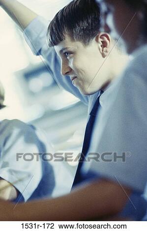 Stock Image - Boy raising his hand in class. Fotosearch