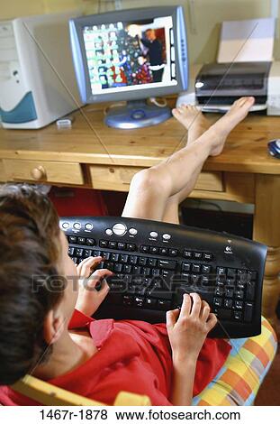 Boy sitting in front of a computer monitor operating a computer keyboard View Large Photo Image Stock Photo - Boy sitting in front of a computer monitor operating a computer keyboard. Fotosearch